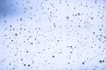 Dirty window glass with drops of rain. Atmospheric blue light background with raindrops. Droplets...