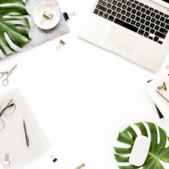 Home office workspace frame with laptop, tropical leaves Monstera, clipboard, notebook and accessories on white background. Flat lay, top view
