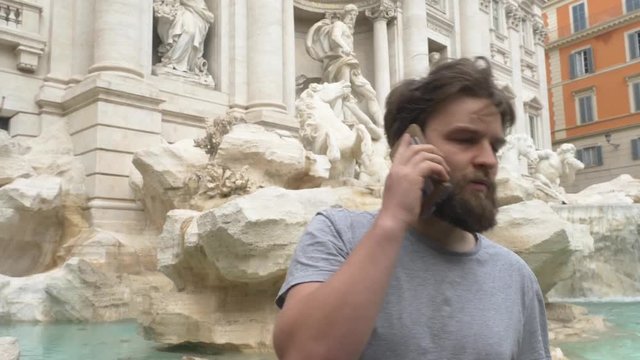 Young Tourist Talking On A Smartphone At The Trevi Fountain.