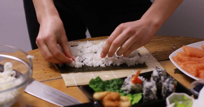 Close up of a woman preparing homemade sushi, the Japanese delicacy.