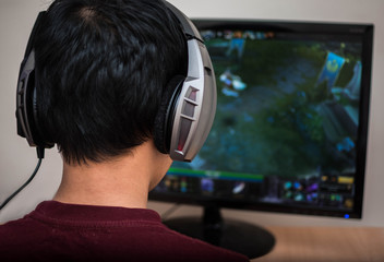 Gamer in headphone playing video game at home.