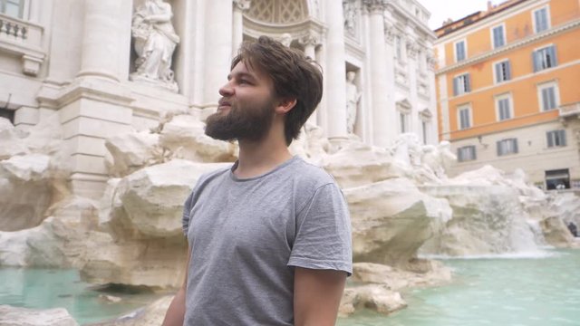 Young Male Tourist Tossing Coin Over His Shoulder Into The Trevi Fountain. Slow Motion.