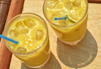 Fresh mango cocktail with ice cubes. Two glasses of refreshing drink on a wooden table. Top view. Refreshing drinks in summer time. Close up. Beautiful image. Food Photography