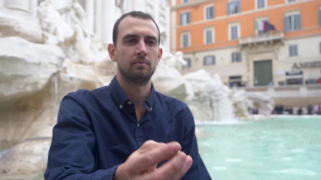Male Tourist Makes A Wish While Tossing Coin Into A Fountain.