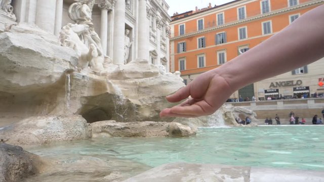 Close Up Hand Throwing Coin Into A Fountain.