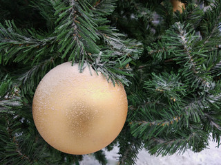 big Golden decoration hanging on the Christmas tree branch