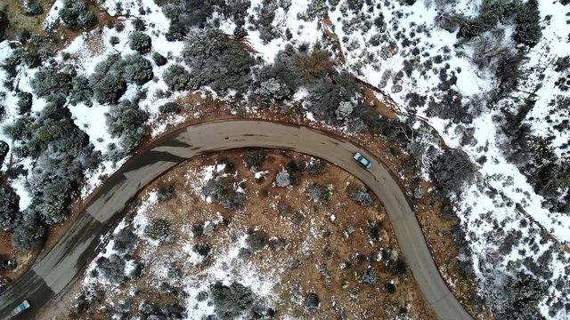 Aerial shot of two cars passing each other while driving up a windy road.
