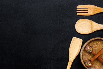 Woodenware set with pan, spoons and forks on black background top view mock up