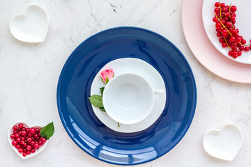 set-up table with plates, wineberry and flower on stone background top view