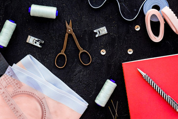 Tailor shop with thread, scissors, fabric. Sewing as hobby. Black background top view