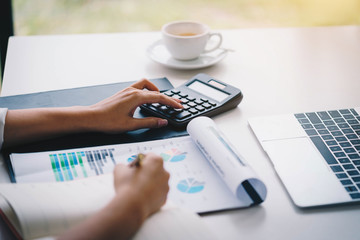 Fototapeta na wymiar Business woman working with financial data hand using calculator and writing make note with calculate.Business financial and accounting concept.