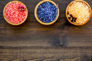 Colorful bath salt pink and blue on dark wooden background top view copy space