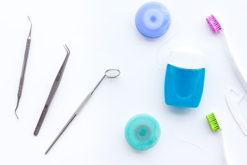 Tooth care with toothbrush, dental floss and dentist instruments. Set of cleaning products for teeth on white background top view