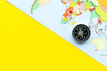 Direction concept with compass and map on yellow background top view