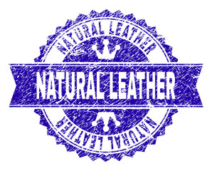 NATURAL LEATHER rosette seal watermark with grunge texture. Designed with round rosette, ribbon and small crowns. Blue vector rubber watermark of NATURAL LEATHER label with corroded texture.