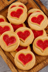 Top view of traditional Linzer pastry with red jam on a rustic wooden background decorated with berries, hearts.