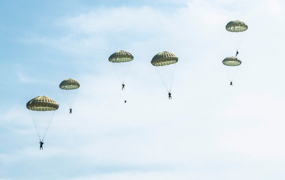 Many soldiers with parachutes in the sky.