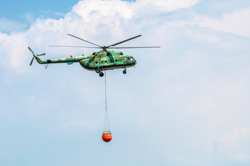 Green firefighting helicopter transporting water. © Degimages