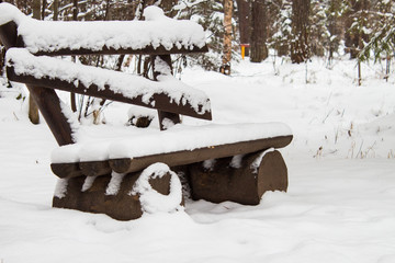 Old empty wooden  bench in snow-covered park. Winter background. Outdoors.
