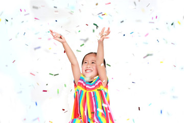 Obraz na płótnie Canvas Smiling little Asian kid girl with many falling colorful tiny confetti pieces on white background. Happy New Year or Congratulation Concept.