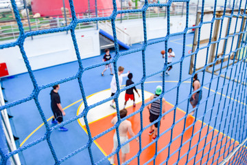 Netting around basketball court and a game in session, onboard a cruise ship