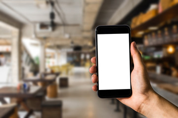 Hand holding white mobile phone with blank white screen  in cafe.