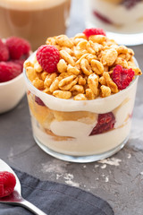 Fresh yoghurt with rasberries and coffee in clear glass. Raspberries in white bowl. Healthy morning breakfast.