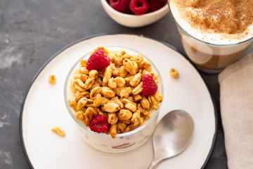 Fresh yoghurt with rasberries and coffee in clear glass. Raspberries in white bowl. Healthy morning breakfast.