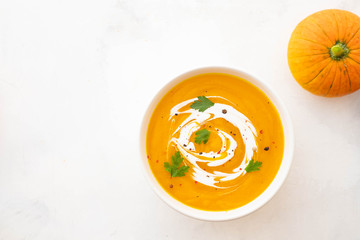 Pumpkin soup with cream and pumpkin seeds isolated on white background. Autumn concept.