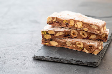 Traditional italian festive chocolate torrone or nougat with nuts close up. Copy space.