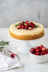 Classic New York Cheesecake with cranberry, rosemary and tea on White Concrete Background, copy spase. Tea and Cheesecake