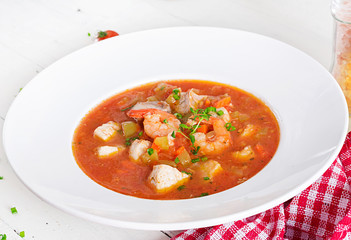 Brazilian food: Moqueca capixaba of fish and bell peppers in spicy coconut sauce  in a plate on a white wooden table. Brazilian fish stew.
