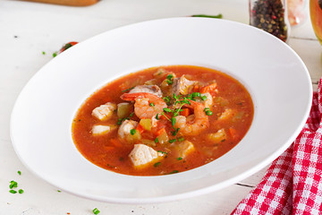 Brazilian food: Moqueca capixaba of fish and bell peppers in spicy coconut sauce  in a plate on a white wooden table. Brazilian fish stew.