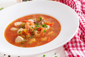 Brazilian food: Moqueca capixaba of fish and bell peppers in spicy coconut sauce  in a plate on a white wooden table. Brazilian fish stew.