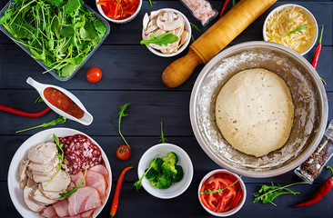 Italian pizza.  Dough and pizza ingredients. Dough, cheese, tomatoes, broccoli, mushrooms, salami, ham, chicken fillet or bakery cooking. Top view