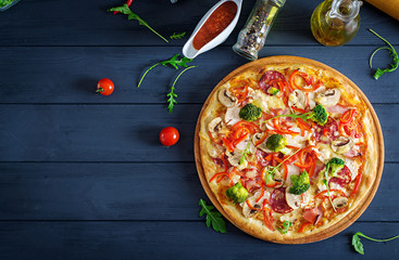 Fresh italian pizza with chicken fillet, mushrooms, ham, salami, tomatoes, broccoli, cheese on on...