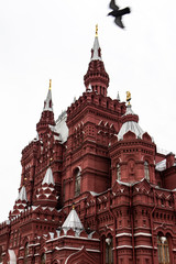 Fototapeta na wymiar Bird flying over a massive red brick landmark in Moscow
