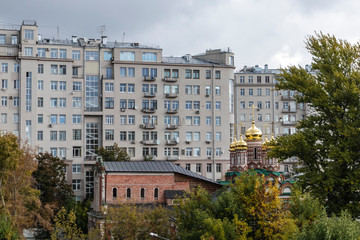 Fototapeta na wymiar Massive residential building with orthodox church and park on a typical Moscow cityscape building Russia