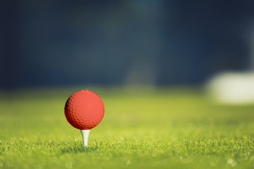 Close up of golf ball on tee. Concept of the fresh start. Coral accent - color of the year 2019