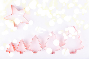 Flatlay with star and row of holiday tree copper cookie cutters on white sparkling background. Holiday, Christmas and New Year concept. Cozy homey details