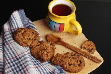 Cookies with chocolate chips and tea against dark background