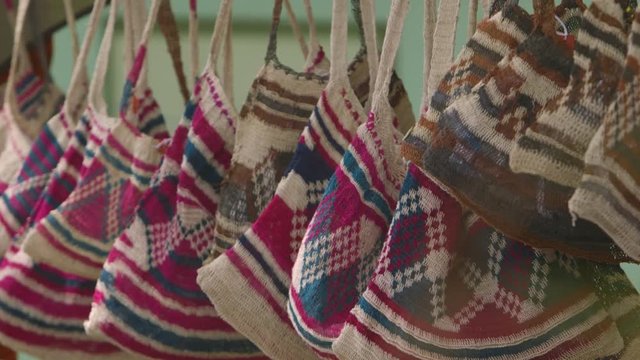 a closeup shot of small cloth/jute shopping bags probably handwoven hanging on a line 