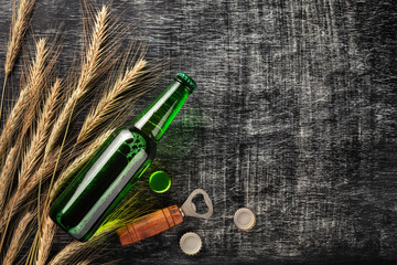 A bottle of beer with spikelets and opener on a black scratched chalk board