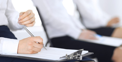 Obraz premium Business people taking part at conference or training at office, close-up. Women sitting on chairs and making notes like at queue or meeting 