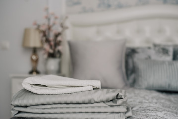 stacks grey white bed linen and towels textiles clothing on bed. Comfort, design, cozy bedroom