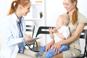 Fototapeta premium Doctor examining a little boy with stethoscope. Mother holds her son on her lap. Motherless and medicine concept
