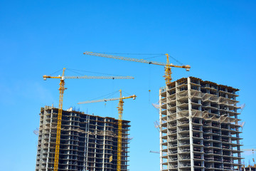 Building cranes and building under construction against sky.