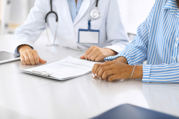 Doctor and patient talking and discussing health treatment while sitting at the desk. Medicine and health care concept