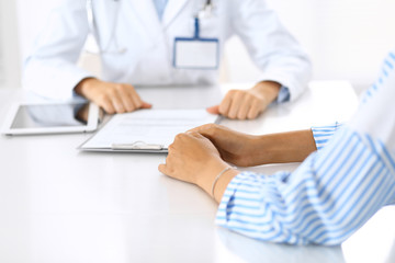 Doctor and patient talking and discussing health treatment while sitting at the desk. Medicine and health care concept