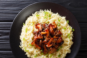 Delicious fried shiitake mushrooms with garlic and sesame seeds served with rice closeup on a plate. Horizontal top view